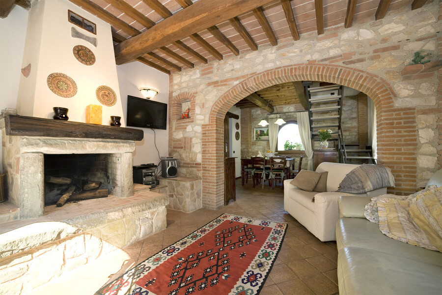 Das Wohnzimmer des Ferienhauses in der Toskana La Capinera besitzt einen großen Kamin, der zu gemütlichen Abenden am offenen Feuer einlädt